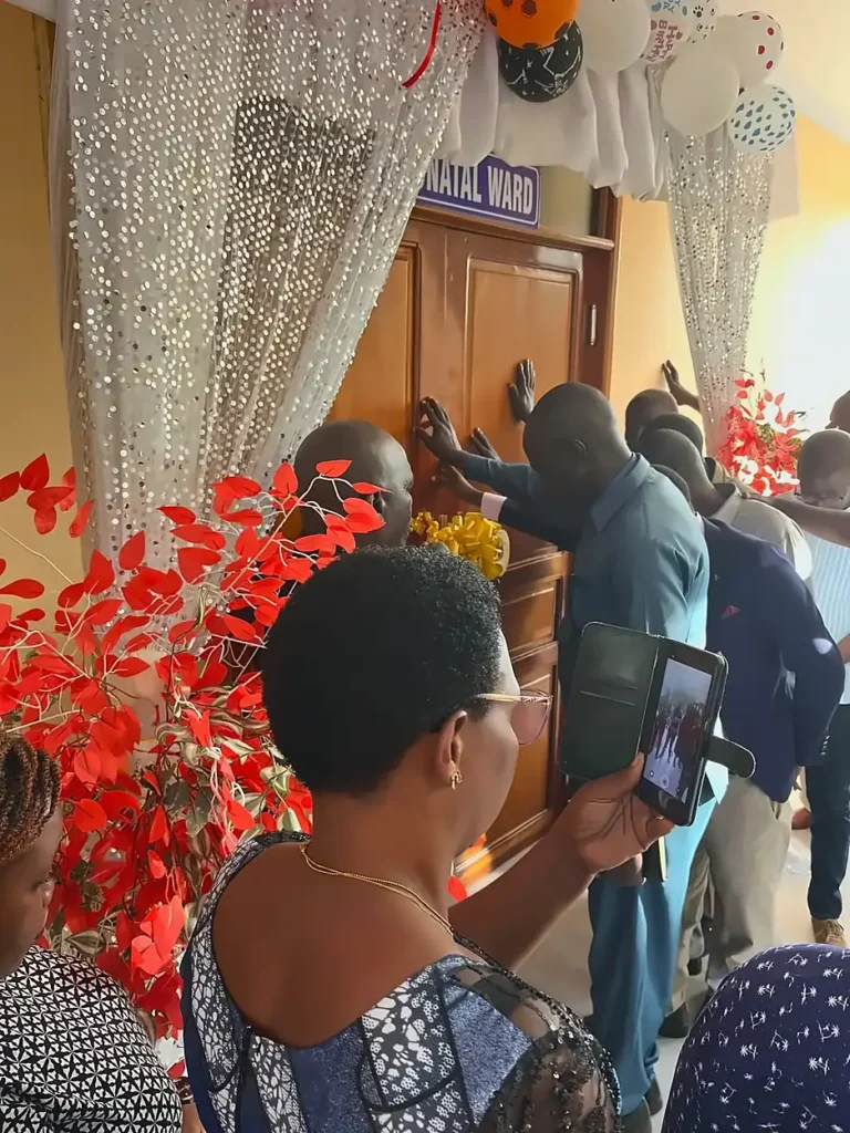 People praying in front of a wooden door during the Shirati Opening ceremony.