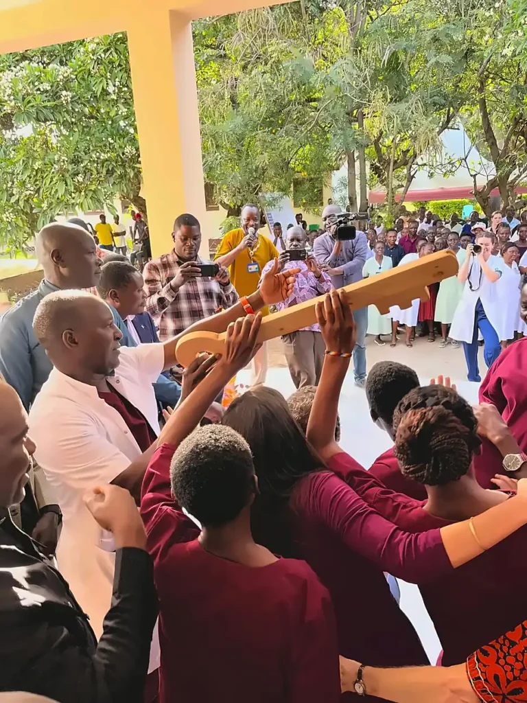 A group of people holding a wooden key during the Shirati Opening ceremony outside.